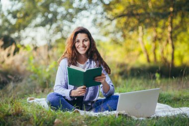 Nostaljik genç kız parkta oturmuş kitap okuyor.