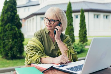 Senyor güzel iş kadını bir sandalyede oturuyor ve not defterine telefonla notlar alıyor.