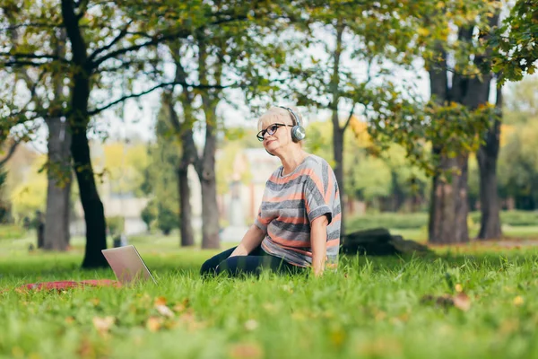 Oudere Vrouw Rustend Het Park Zittend Het Gras Met Telefoon — Stockfoto