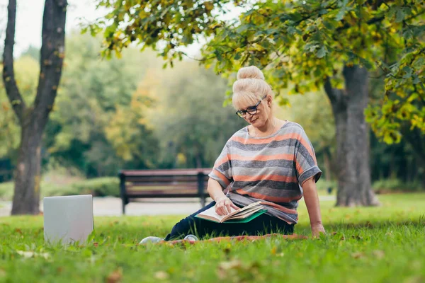 Oudere Vrouw Rustend Het Park Zittend Het Gras Met Telefoon — Stockfoto
