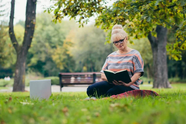 Oudere Vrouw Rustend Het Park Zittend Het Gras Met Telefoon — Stockfoto