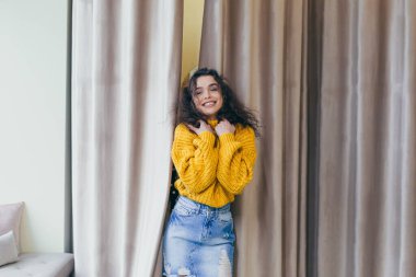 Mağazada farklı kıyafetler deneyen genç ve güzel bir kadın. Alışverişe bayılıyor.