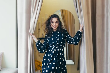 Mağazada farklı kıyafetler deneyen genç ve güzel bir kadın. Alışverişe bayılıyor.