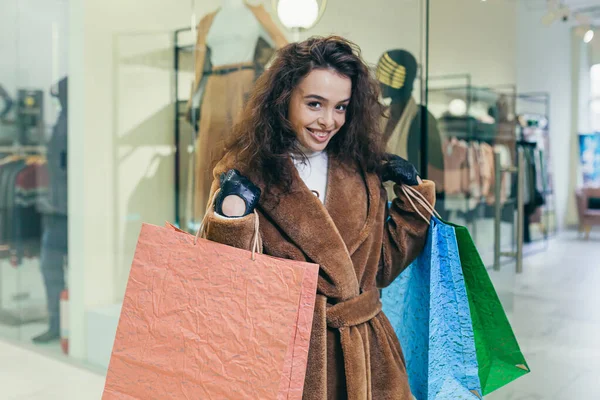 若い美しい女性は 商品と色の袋を保持店を残し 彼らの購入に満足しているようだ — ストック写真