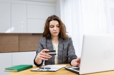 Kadın evde dinleniyor, internetten alışveriş yapıyor, dizüstü bilgisayar ve kredi kartı kullanıyor.