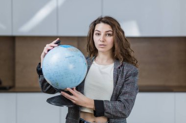 Elinde bir küre tutan ve gülümseyen güzel bir kadın ofiste.