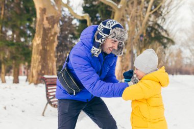 Bir adam ve bir çocuk kışın parkta karın tadını çıkarırlar, baba ve oğul birlikte eğlenirler.