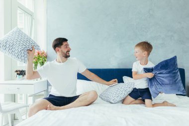 Koca baba çocuklarıyla oynuyor, iki küçük erkek kardeş, büyük bir yatak odasında.