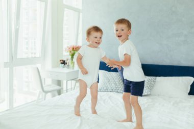 İki küçük erkek kardeş anne babalarının yatak odasında oynuyorlar.