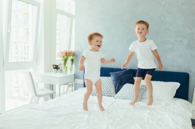 İki küçük erkek kardeş anne babalarının yatak odasında oynuyorlar.