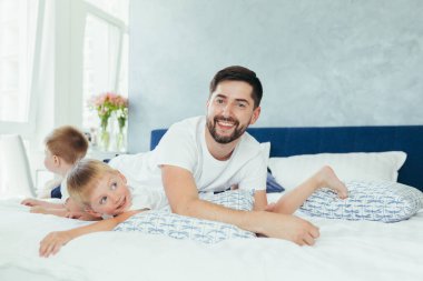 Koca baba çocuklarıyla oynuyor, iki küçük erkek kardeş, büyük bir yatak odasında.