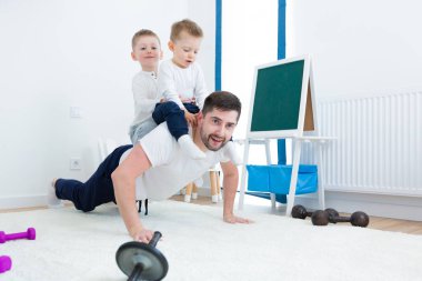 Genç adam baba, iki küçük oğluyla sabah egzersizi yapıyor. Kreşte birlikte vakit geçirin.