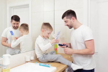 Baba ve oğul sabah dişlerini fırçalarlar, birlikte eğlenirler.