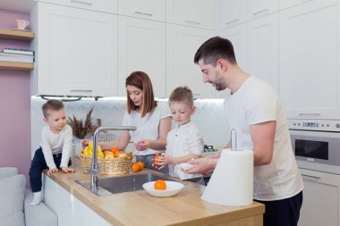 Mutfakta birlikte kahvaltı hazırlayan iki oğlu olan genç ve mutlu bir aile.