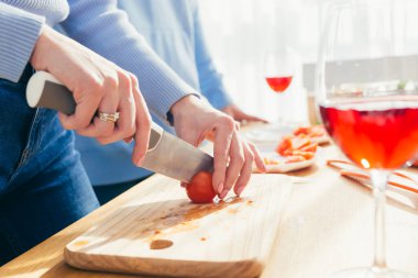 Yakın plan fotoğraf, eller sebzeleri salataya kesiyor.