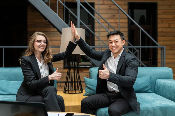 Man and woman smiling colleagues celebrate business victory, achieving the goal in the workplace, giving five, successful teamwork, business partners start working on a new project, good brainstorming results, the concept of victory
