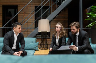 Üç çok ırklı işadamı, bilişim teknolojileri ve konferans odasındaki bir iş uygulamasında dizüstü bilgisayar kullanarak hukuki danışmanlık hizmetleri alanında bir iş sözleşmesi yapmayı düşünüyorlar..