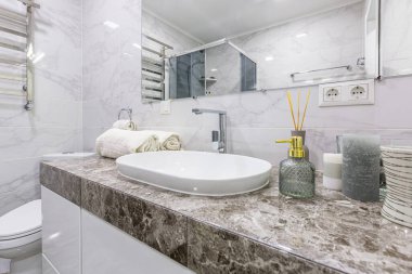 Duşlu, küçük bir dairede, beyaz mermer döşemeleri olan modern bir banyo.