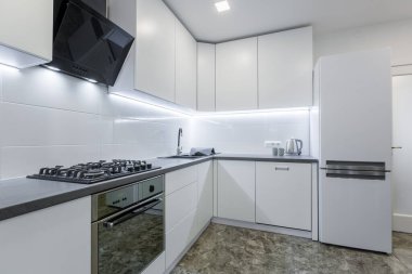 İç mekan fotoğrafı, modern mutfak, açık beyaz renkler, yerde siyah mermer fayanslar, küçük bir daireye yerleştirilmiş.