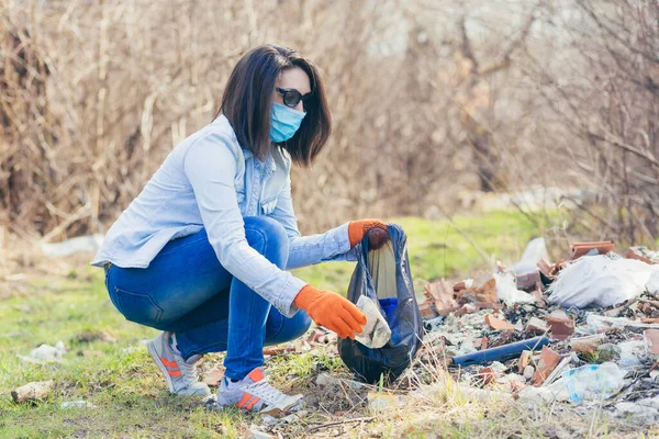 若い女性ボランティアが森や公園でプラスチックごみを集め ボランティアがビニール袋を持ってゴミを集める — ストック写真