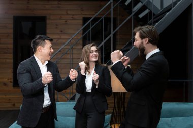  Takım elbiseli iş adamları başarılı bir iş anlaşması planladıktan sonra şirket ofisinde hissedarlarla buluşup dans ediyor ve gülümsüyor. İş, sözleşme