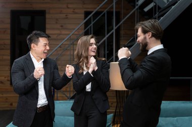  Takım elbiseli iş adamları başarılı bir iş anlaşması planladıktan sonra şirket ofisinde hissedarlarla buluşup dans ediyor ve gülümsüyor. İş, sözleşme