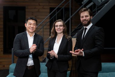  Takım elbiseli iş adamları başarılı bir iş anlaşması planladıktan sonra şirket ofisinde hissedarlarla buluşup dans ediyor ve gülümsüyor. İş, sözleşme