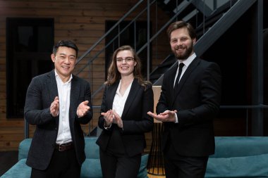  Takım elbiseli iş adamları başarılı bir iş anlaşması planladıktan sonra şirket ofisinde hissedarlarla buluşup dans ediyor ve gülümsüyor. İş, sözleşme