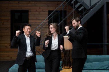  Takım elbiseli iş adamları başarılı bir iş anlaşması planladıktan sonra şirket ofisinde hissedarlarla buluşup dans ediyor ve gülümsüyor. İş, sözleşme