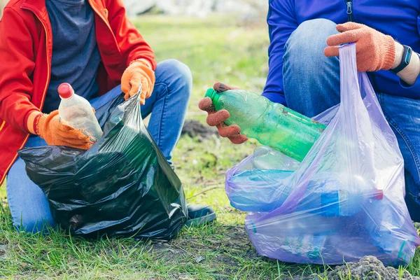 公園や森でゴミを集めているボランティアの男と息子の終わりです 生態学の概念は 2人の手のゴミ袋にペットボトルを置く — ストック写真