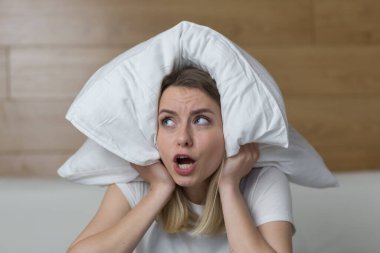 Evde ince duvarlar, ses yalıtımı olmayan bir daire, komşularda tamirat, tahriş olmuş kadın koltuk örtüsü kulakları ve gürültülü komşulardan rahatsız olan eller sessizlik istiyor. kızgın kadın