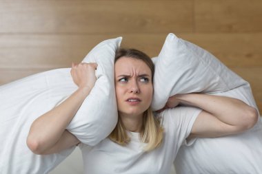 Evde ince duvarlar, ses yalıtımı olmayan bir daire, komşularda tamirat, tahriş olmuş kadın koltuk örtüsü kulakları ve gürültülü komşulardan rahatsız olan eller sessizlik istiyor. kızgın kadın