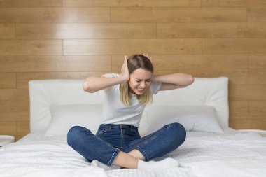 Evde ince duvarlar, ses yalıtımı olmayan bir daire, komşularda tamirat, tahriş olmuş kadın koltuk örtüsü kulakları ve gürültülü komşulardan rahatsız olan eller sessizlik istiyor. kızgın kadın