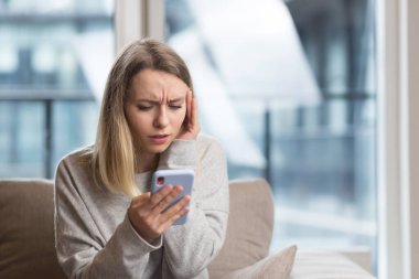 Kanepede oturan genç bir kadın şiddetli bir baş ağrısı ile, telefonla bir doktoru aramaya çalışıyor, ve bu soruna online danışmada bir çözüm bulmaya çalışıyor.