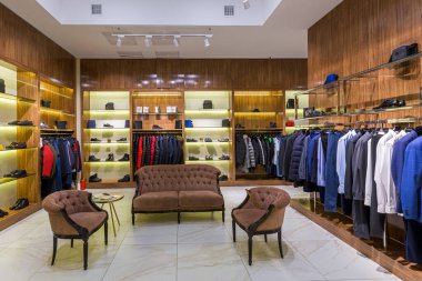 Modern tarzda bir giyim mağazası. Camlı camlı ve askıda giysileri var.