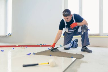 Erkek bir inşaat işçisi büyük seramik bir fayans yerleştirir.