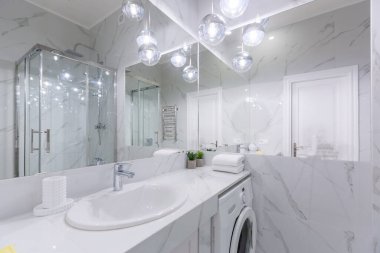 Banyo içi beyaz mermer kiremitler ve modern tarz duşlarla dolu.