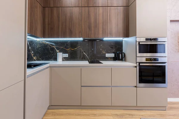 Interior of a stylish modern kitchen in pastel colors, gray, with an insert of black marble