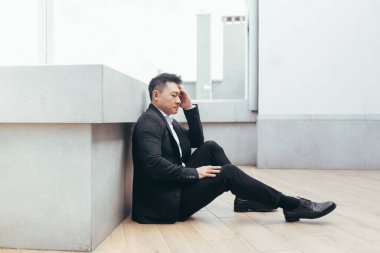 Genç Asyalı bunalımlı adam ofis binasının yanındaki açık havada oturuyor. Üzgün erkek işadamı mali kriz ve karantina yüzünden işini kaybetti. İş adamının sorunları var.