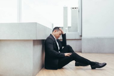 Genç Asyalı bunalımlı adam ofis binasının yanındaki açık havada oturuyor. Üzgün erkek işadamı mali kriz ve karantina yüzünden işini kaybetti. İş adamının sorunları var.