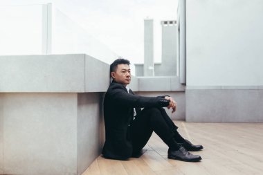 Genç Asyalı bunalımlı adam ofis binasının yanındaki açık havada oturuyor. Üzgün erkek işadamı mali kriz ve karantina yüzünden işini kaybetti. İş adamının sorunları var.