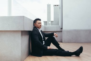 Genç Asyalı bunalımlı adam ofis binasının yanındaki açık havada oturuyor. Üzgün erkek işadamı mali kriz ve karantina yüzünden işini kaybetti. İş adamının sorunları var.