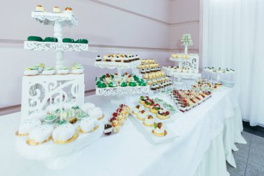 Çikolata. Çöllü beyaz şenlik masası, çilekli tart ve kekler. Düğün için. Resepsiyon Turtaları