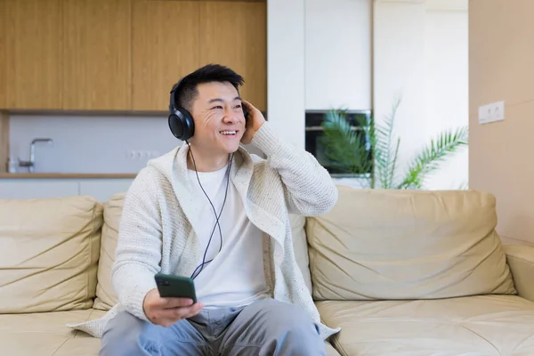 Joven Alegre Asiático Chico Escuchar Música Auriculares Sentado Sofá Casa — Foto de Stock