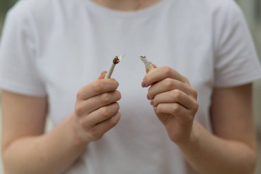 Kadının elleri sigara kırıyor, sigara içmeyi bırakıyor.