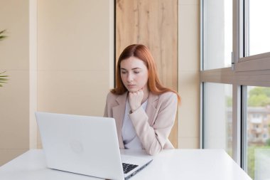 Ofis masasında dizüstü bilgisayarda çalışan ciddi iş kadını.