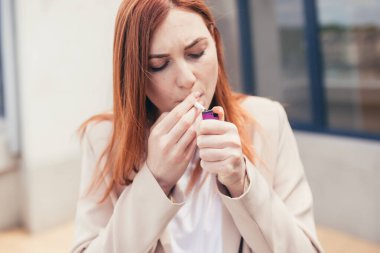 Kadının elleri yakın plan bir sigara yakıyor.