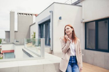 Genç, beyaz bir kadın modern bir ofisin terasında ya da balkonunda duruyor ve esrar içiyor. İş kadını esrar içiyor. Dişi, iş yerindeki stresi hafifletir hafif bir ilaç. İş kadını