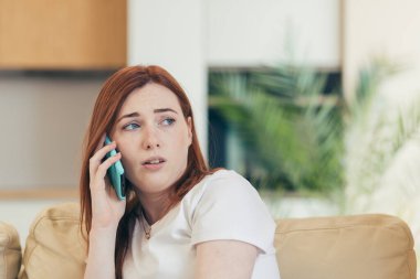 Genç ve güzel bir kadın evde, kanepede tek başına oturuyor, acı ve depresyon hissediyor telefonda bir arkadaşına şikayet ediyor.