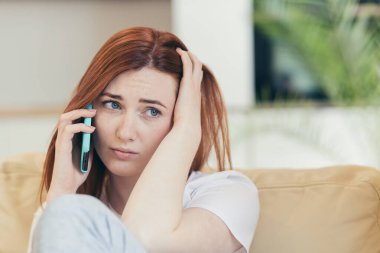 Genç ve güzel bir kadın evde, kanepede tek başına oturuyor, acı ve depresyon hissediyor telefonda bir arkadaşına şikayet ediyor.